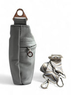 Side view of pale grey, rescued genuine leather crossbody bag with silver strap connector and removable, adjustable strap on a white background
