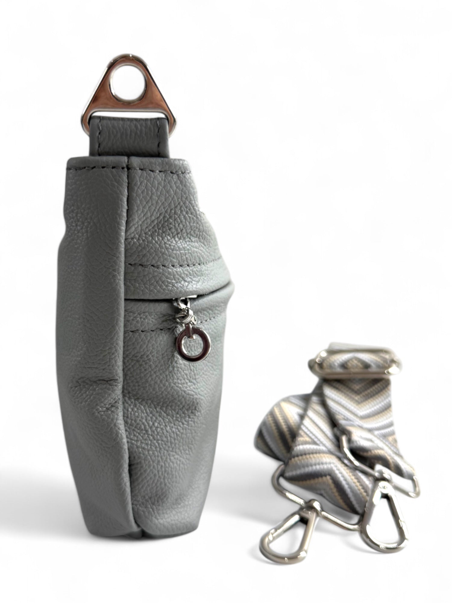 Side view of pale grey, rescued genuine leather crossbody bag with silver strap connector and removable, adjustable strap on a white background