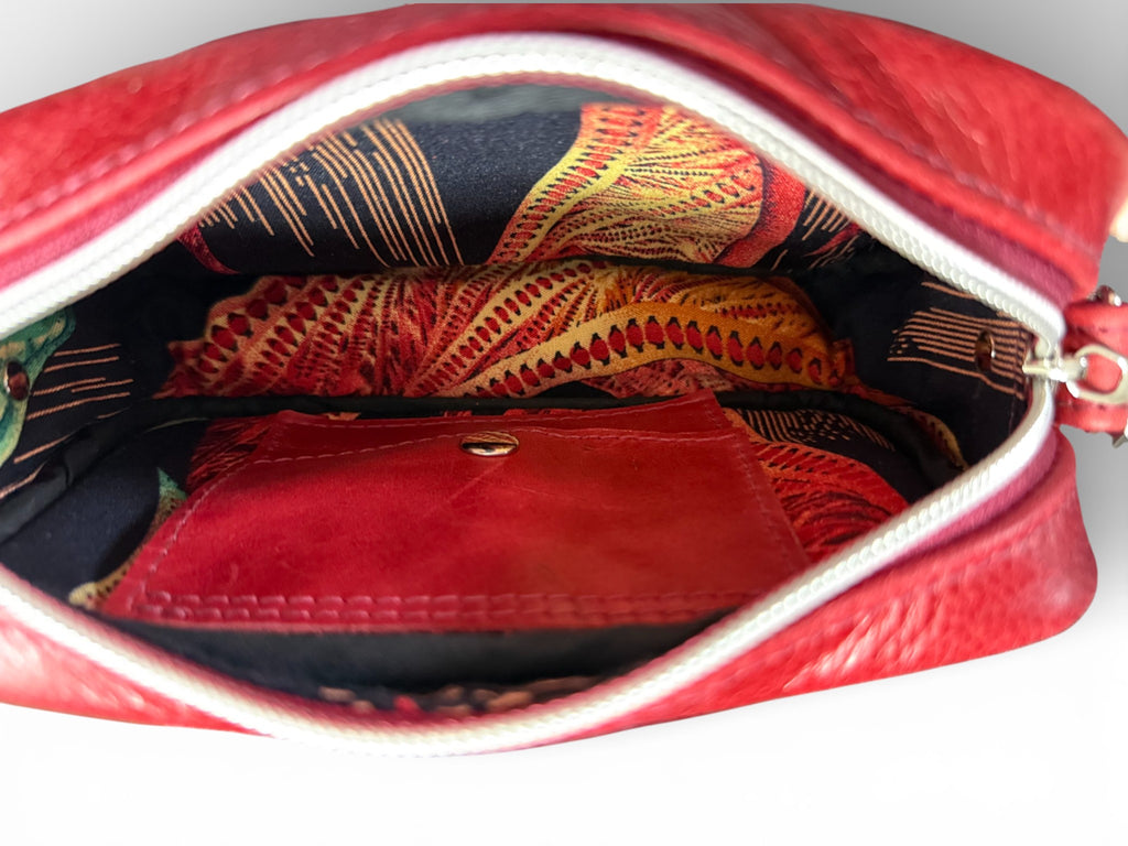 Red leather handbag with a colorful interior lining on a white background. The image highlights the integrated leather purse inside the bag