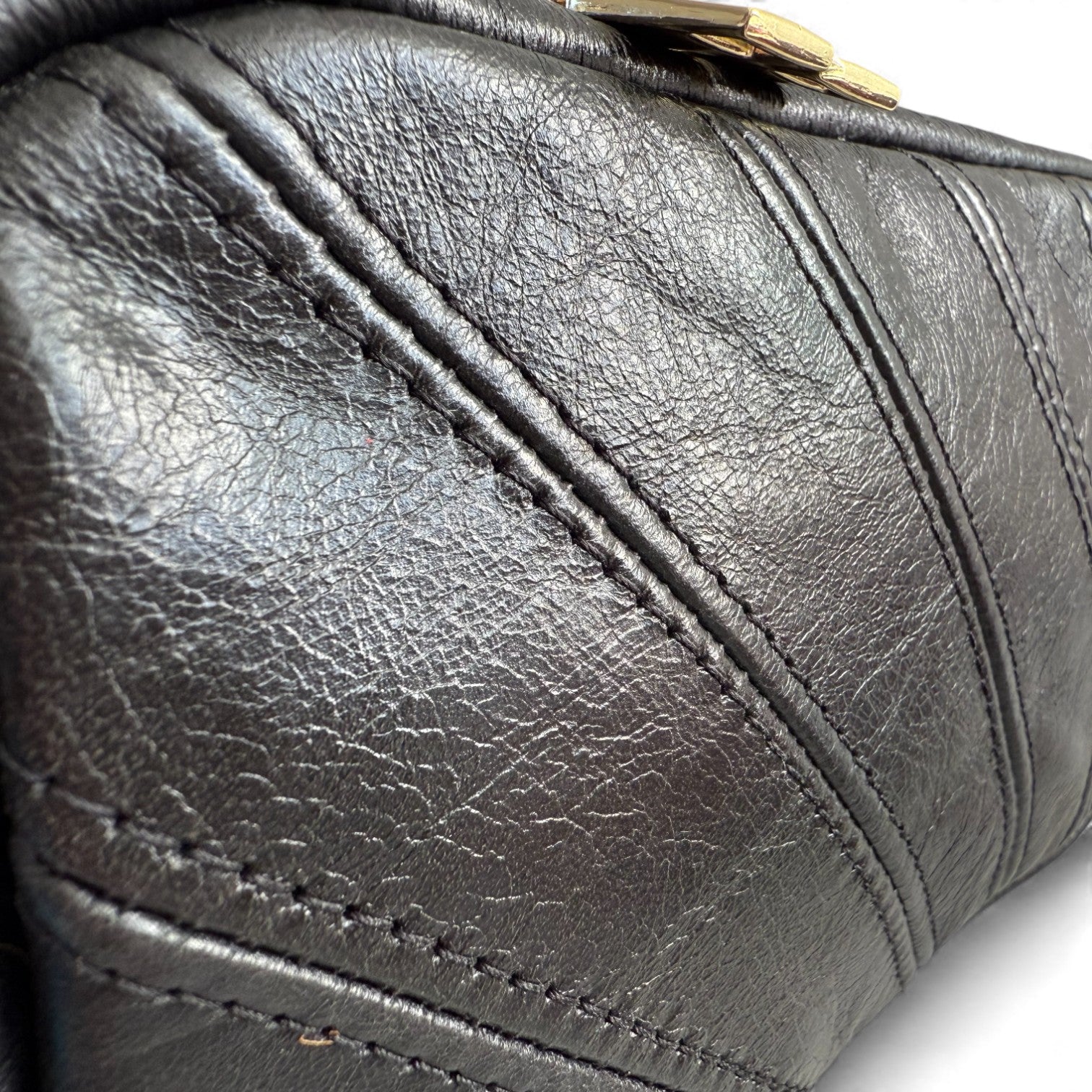 Close-up of a black leather handbag with visible stitching details.