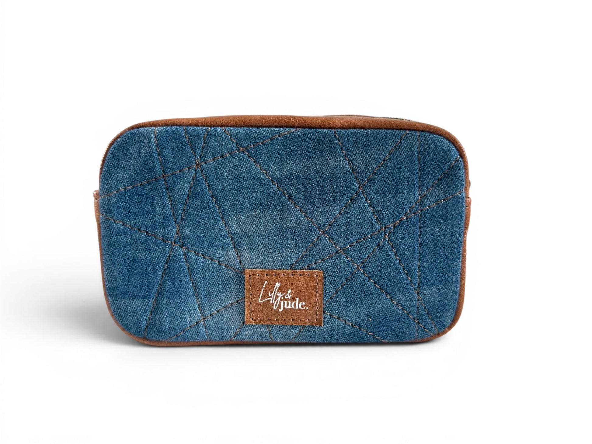 View of the back of the Tiny Harriet, the compact crossbody bag, handcrafted using upcycled blue denim and tan leather gusset. with brown leather patch with the Lilly & Jude logo, sitting on a white background