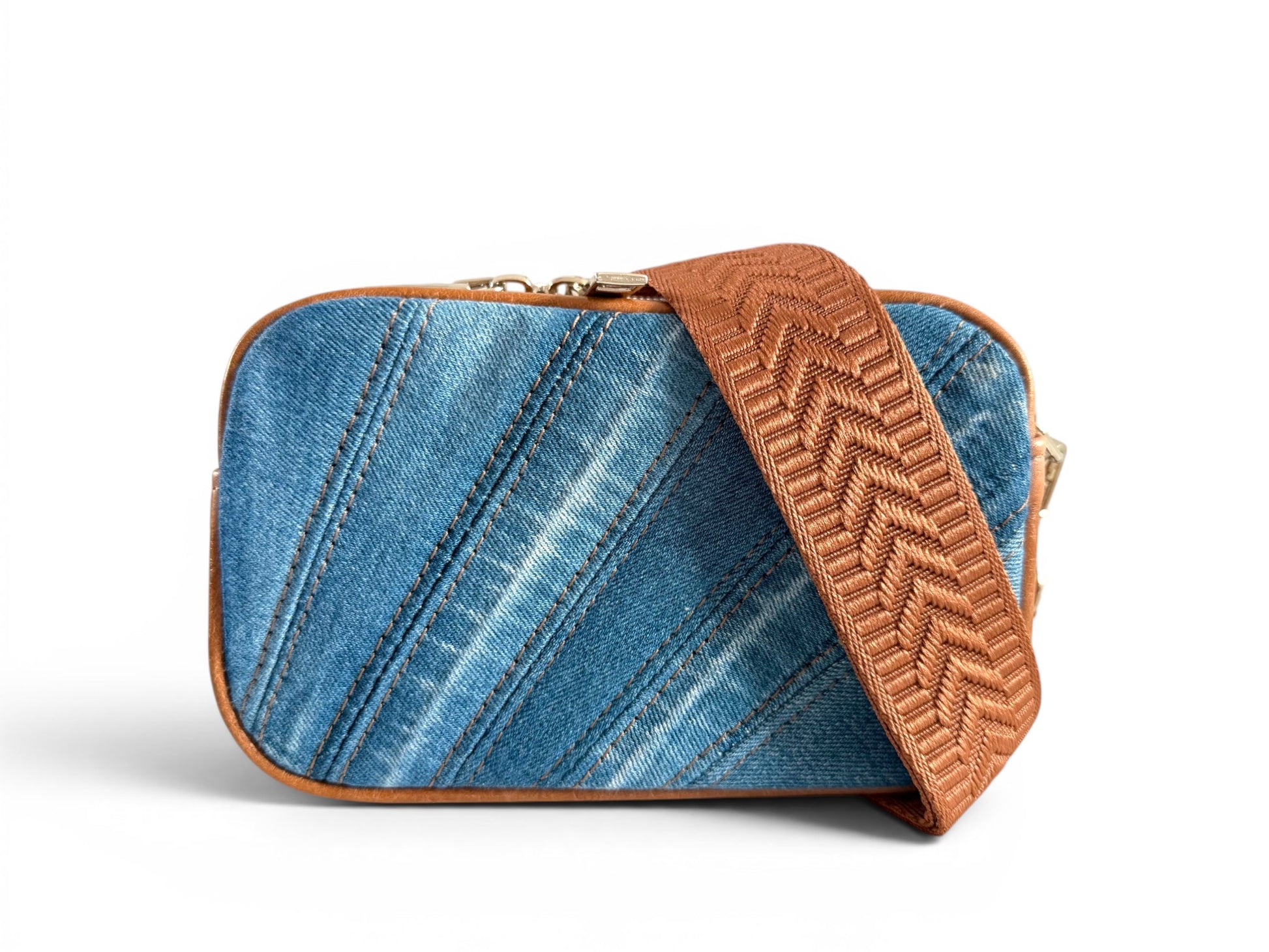 Upcycled denim compact crossbody bag with tan brown leather trim and matching woven strap on a white background