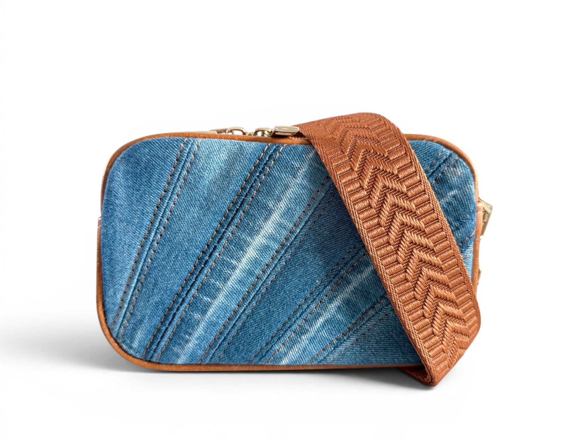 Upcycled denim compact crossbody bag with tan brown leather trim and matching woven strap on a white background