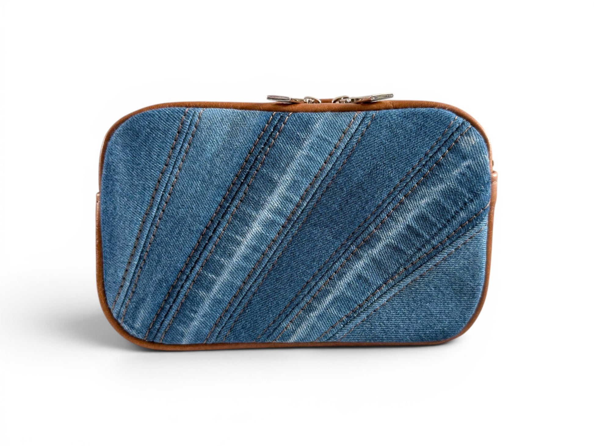 Denim pieced compact crossbody bag with tan brown leather trim on a white background