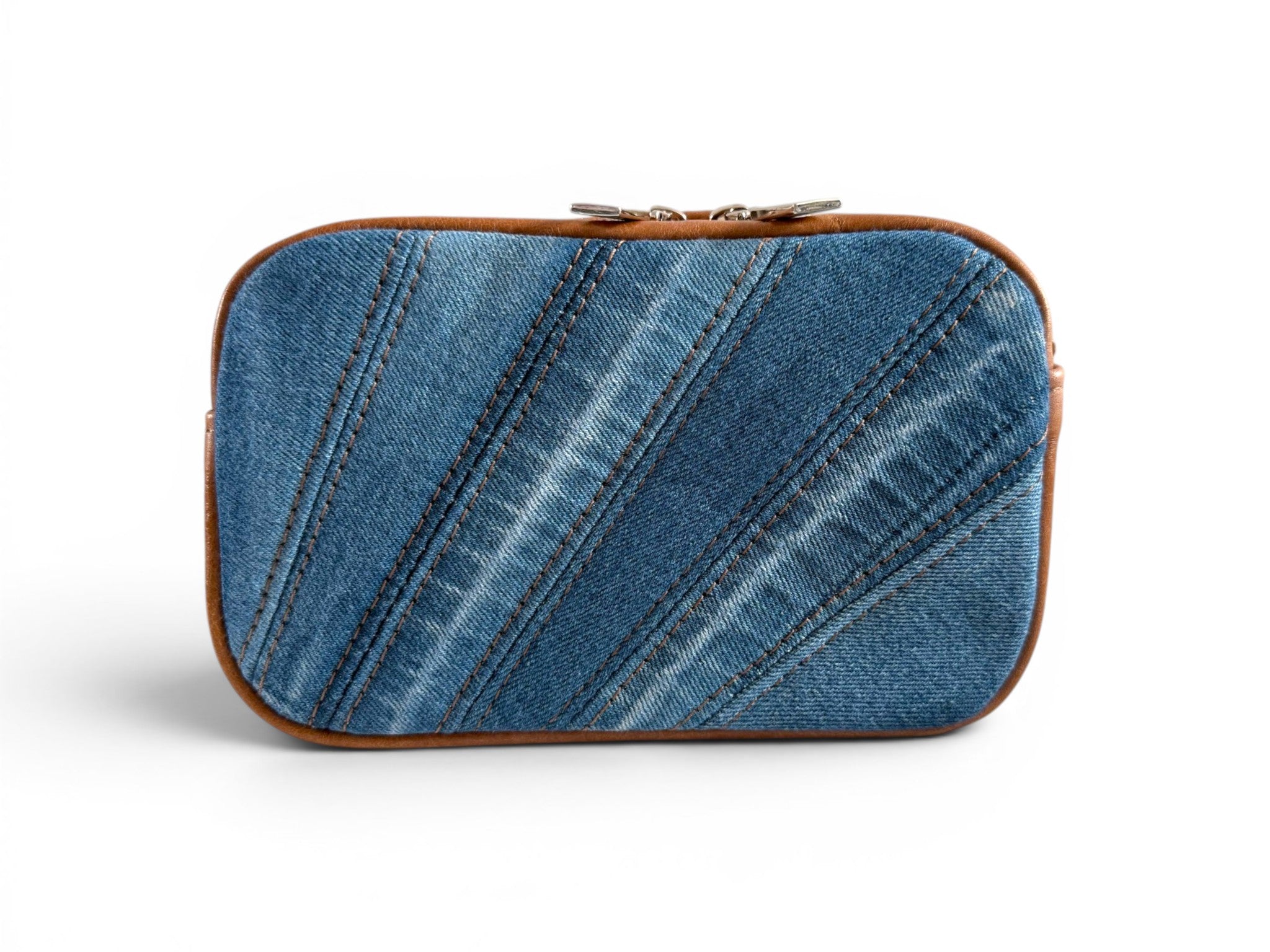 Denim pieced compact crossbody bag with tan brown leather trim on a white background