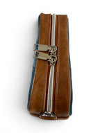 Top view of the bag, showing the leather gusset , silver zipper and hardware, sat on a white background