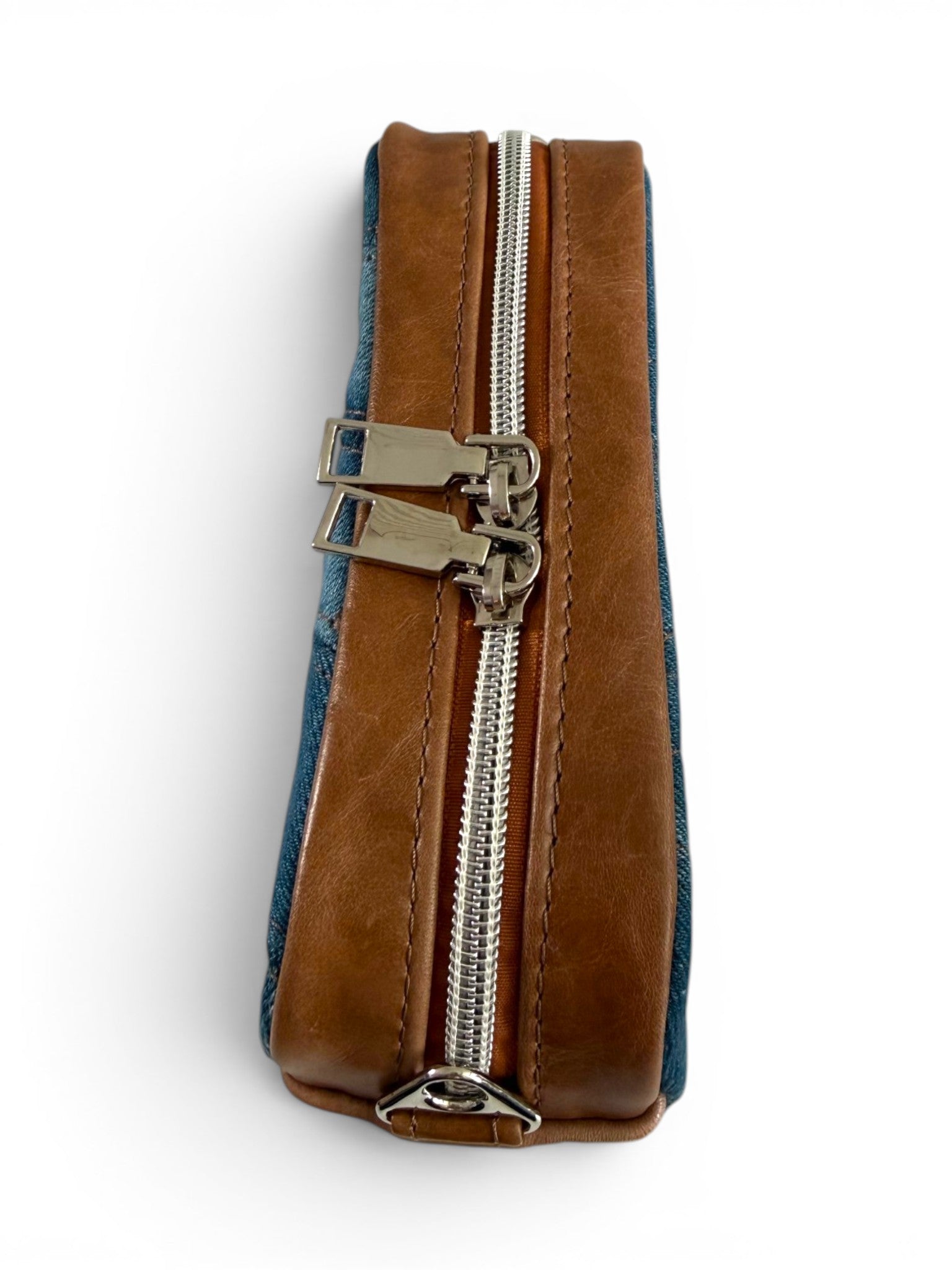 Top view of the bag, showing the leather gusset , silver zipper and hardware, sat on a white background