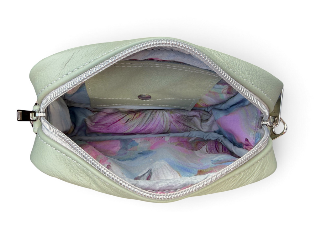 An open sage green pebbled leather pouch with a colorful pastel floral lining, shown against a plain white background.