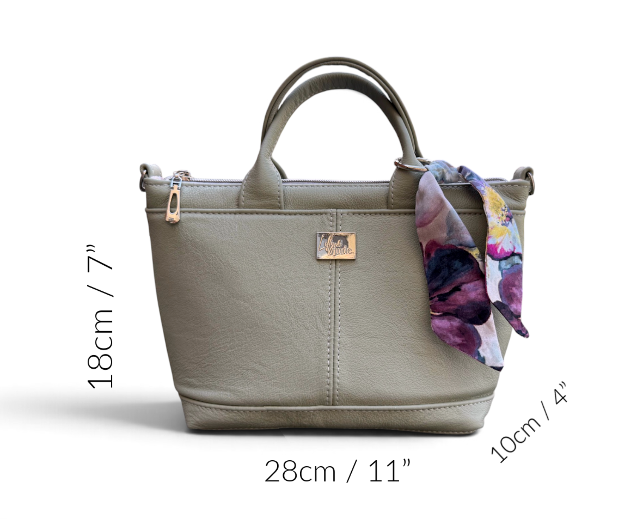 A small, structured tote bag in light sage green leather with dual top handles, a floral silk scarf draped over the side, and dimension labels showing 18cm height, 28cm width, and 10cm depth on a white background.