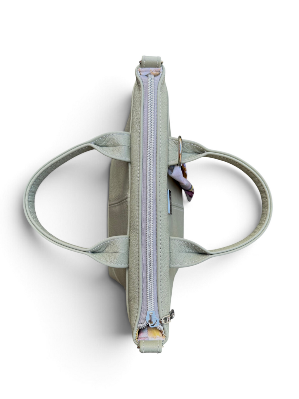 A sage green leather tote bag shown from a top-down view, featuring dual top handles, a central zippered compartment, and a small hanging keychain, set against a plain white background.