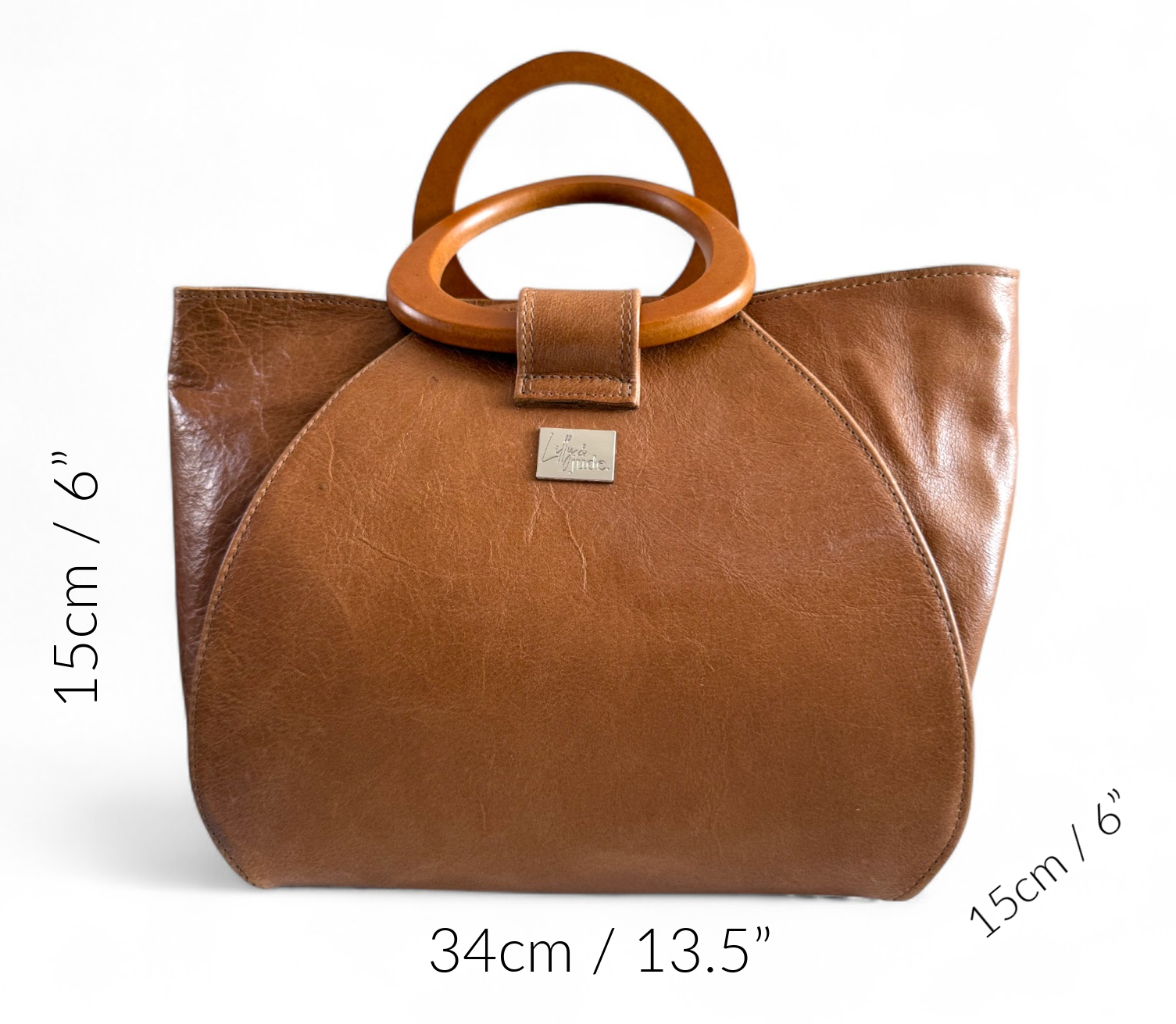 Brown leather handbag with wooden handles and size measurements on a white background. The measurements are:: 34cm/13.5”, 24cm/9.5”, 15cm/6”. UK made by Lilly & Jude.
