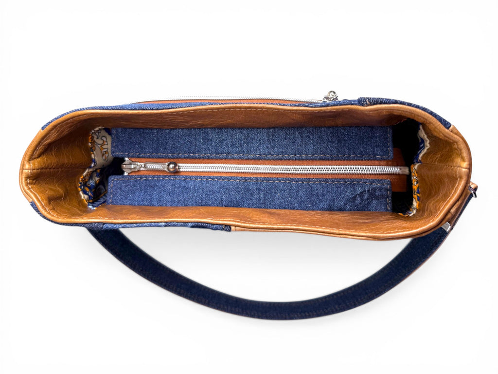 Birds eye view of the Veronica handbag, showing the tan leather interior facing and the denim zipper placket, sat on a white background