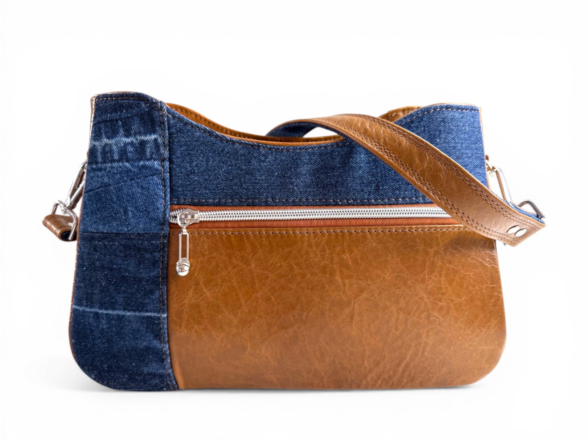 View of the back of the Veronica handbag, made from upcycled denim and tan coloued, rescued leather. It highlights the zipper pocket on the back of the bag