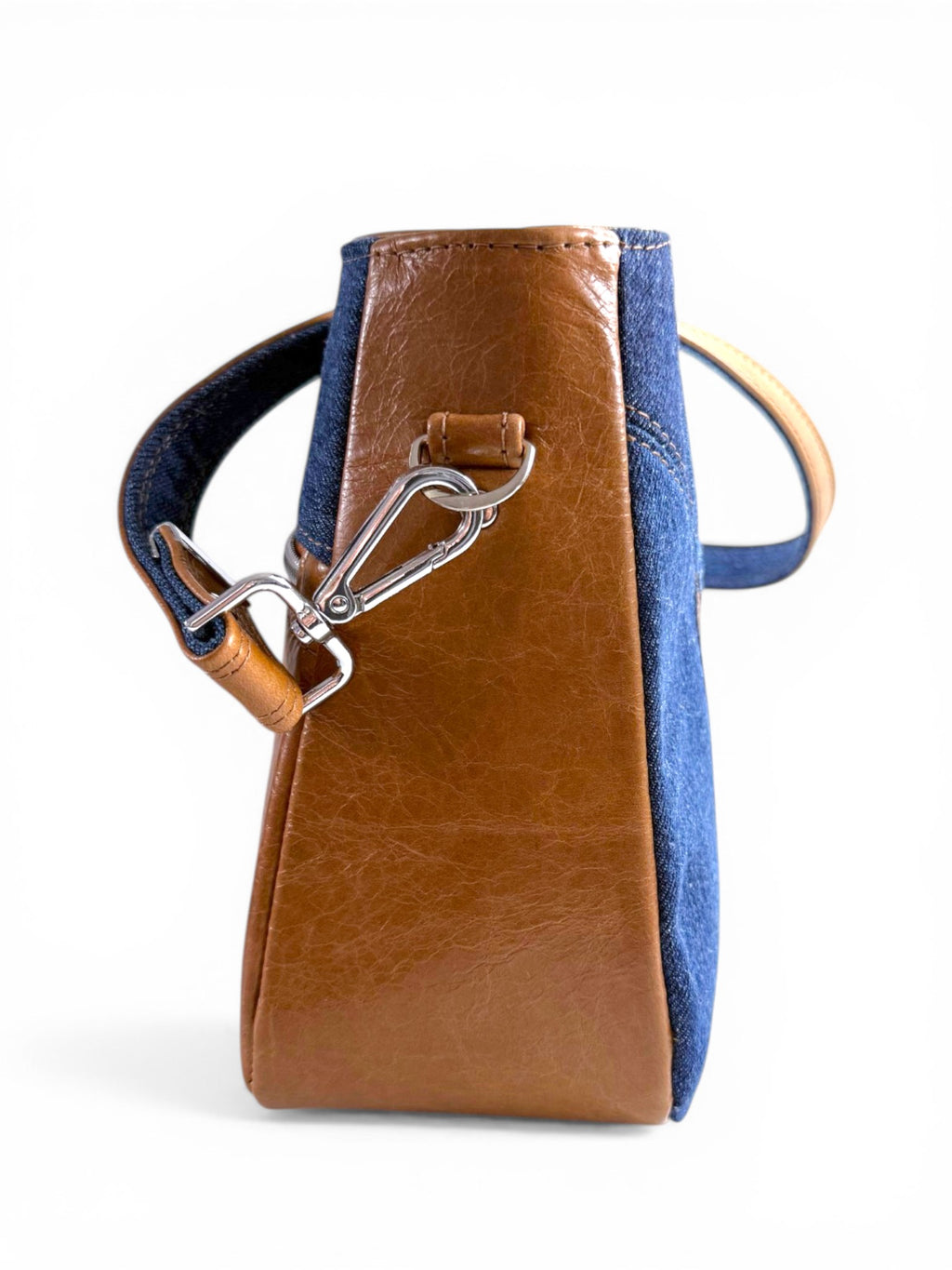 Side view of the Veronica handbag, made from tan brown leather bag and denim, with silver hardware on a white background