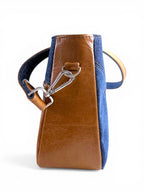 Side view of the Veronica handbag, made from tan brown leather bag and denim, with silver hardware on a white background