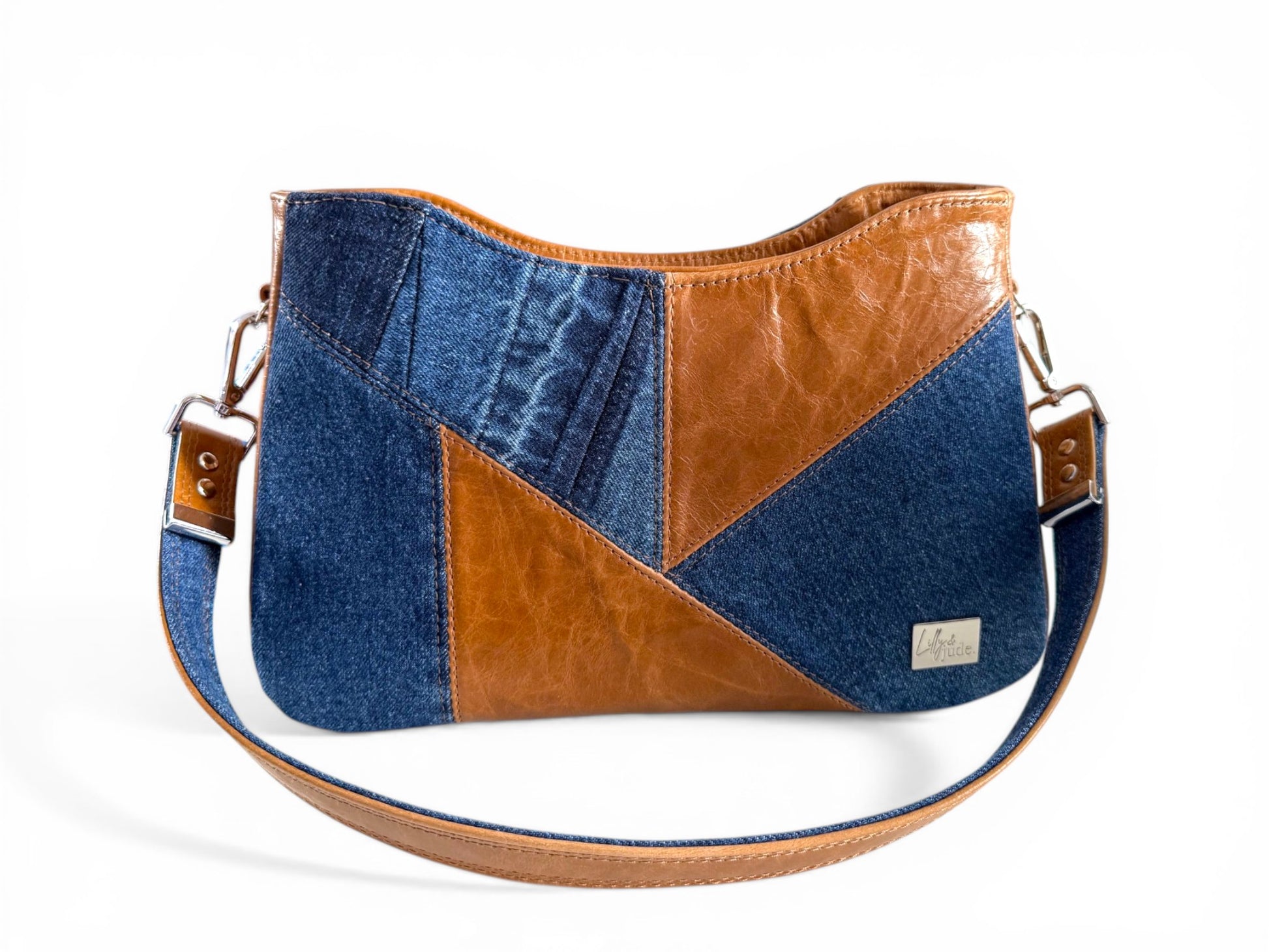 Patchwork handbag with denim and brown leather sections on a white background
