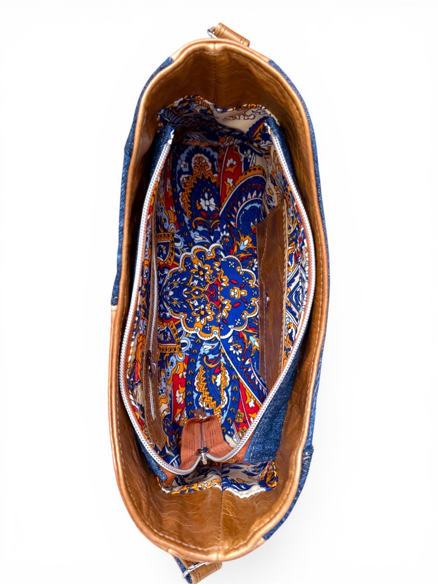 Birds eye view of the Veronica handbag revealing a colorful paisley style patterned lining inside, sat on a white background