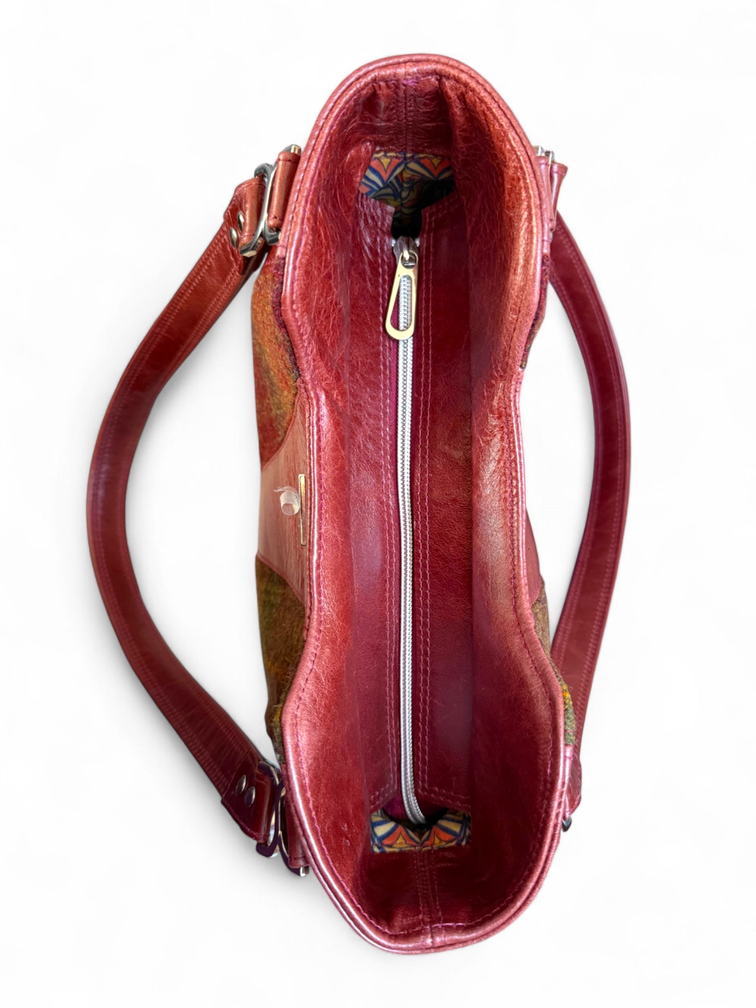 Top view of the burgundy Alaula handbag, showing the silver zippered opening. The bag is sat on a white background