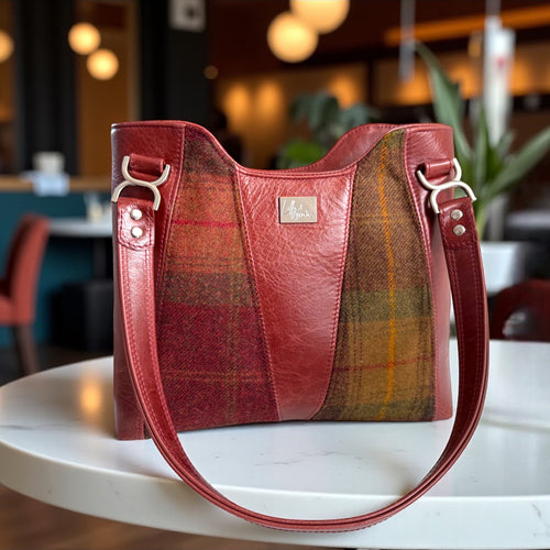 Burgundy red leather and plaid panelled  handbag on a white table in a restaurant setting