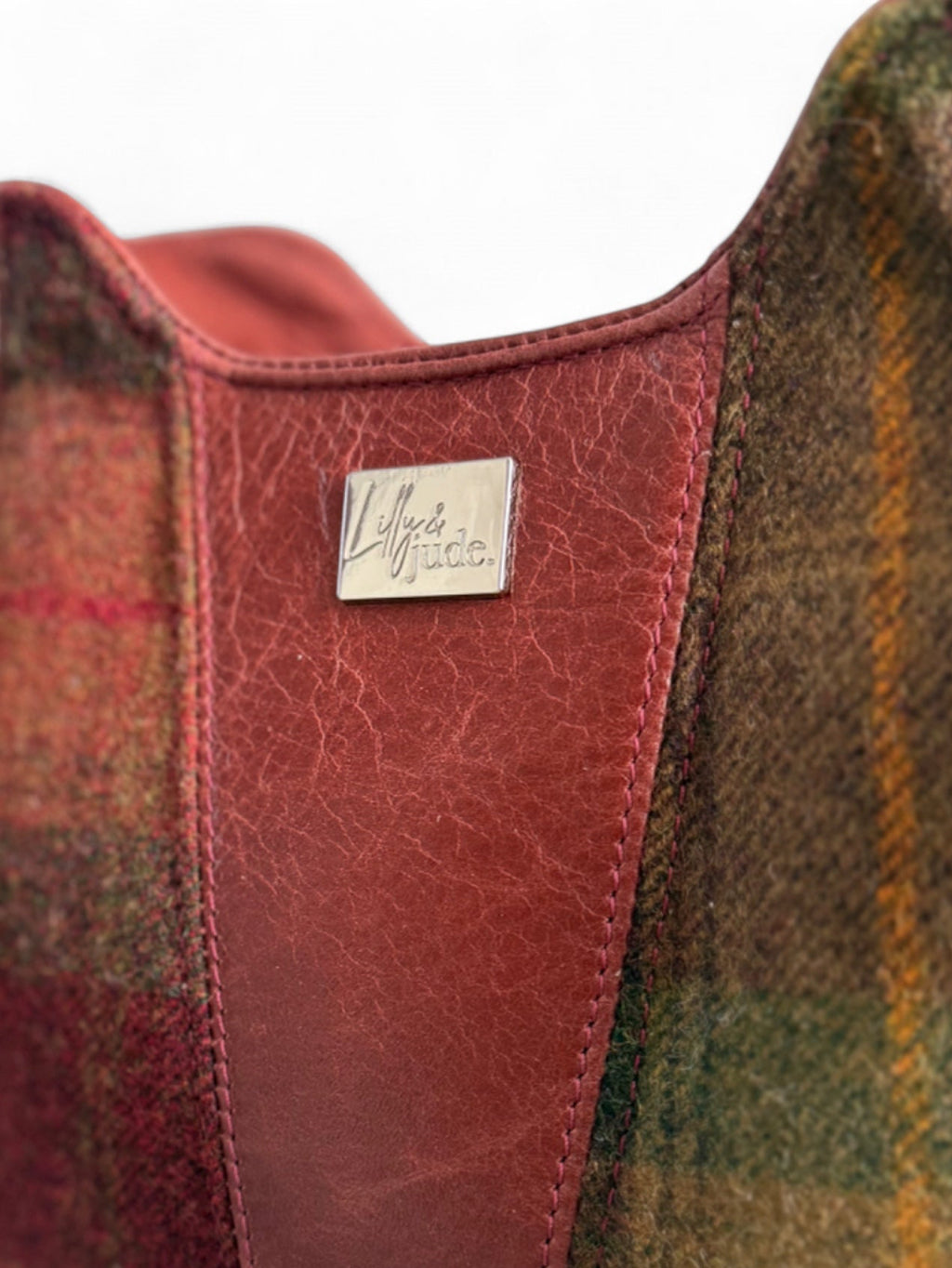 Close-up of the Alaula handbag with plaid pattern and leather panels, featuring a silver Lilly & Jude brand logo.