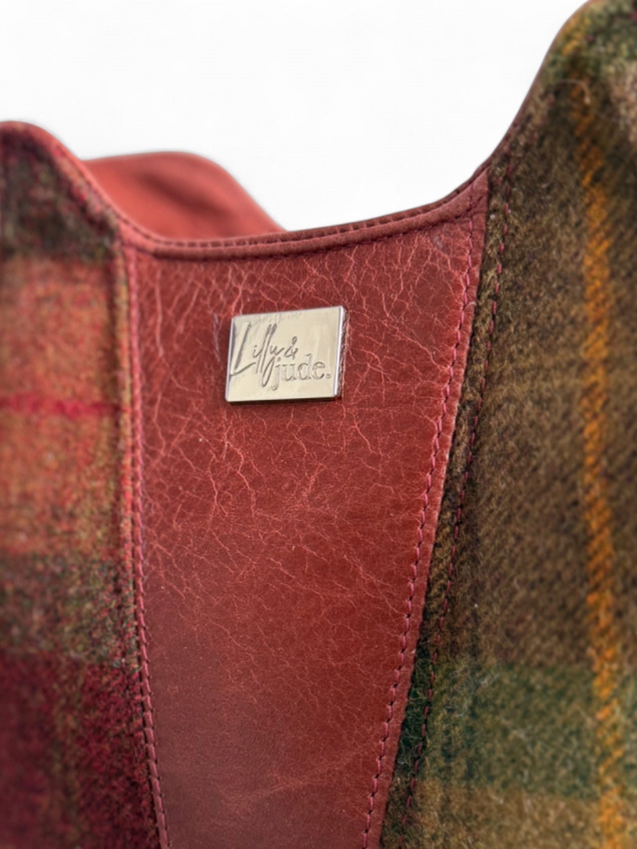 Close-up of the Alaula handbag with plaid pattern and leather panels, featuring a silver Lilly & Jude brand logo.