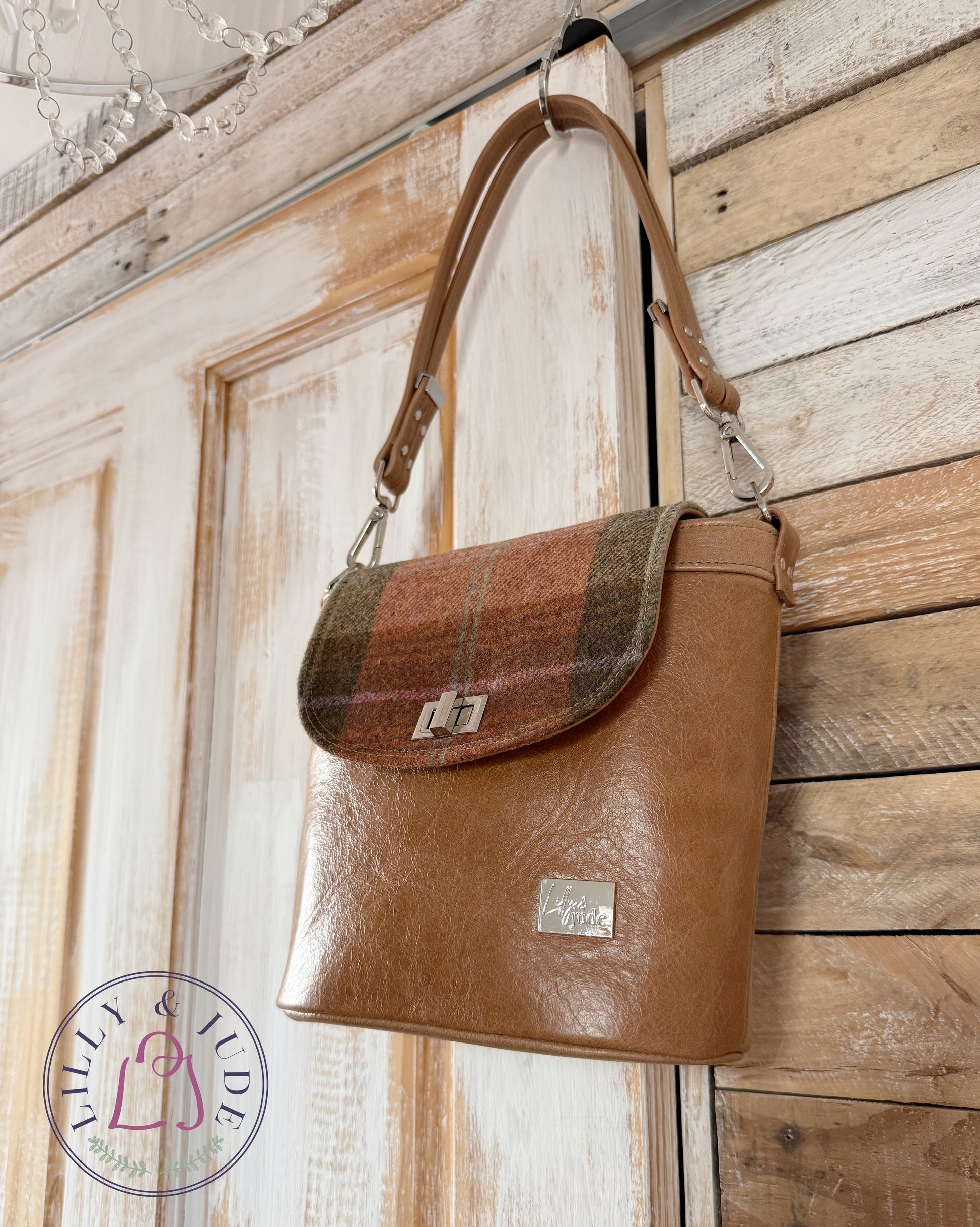 Belle bucket bag hanging on rustic door, tan leather & tweed, silver hardware.
