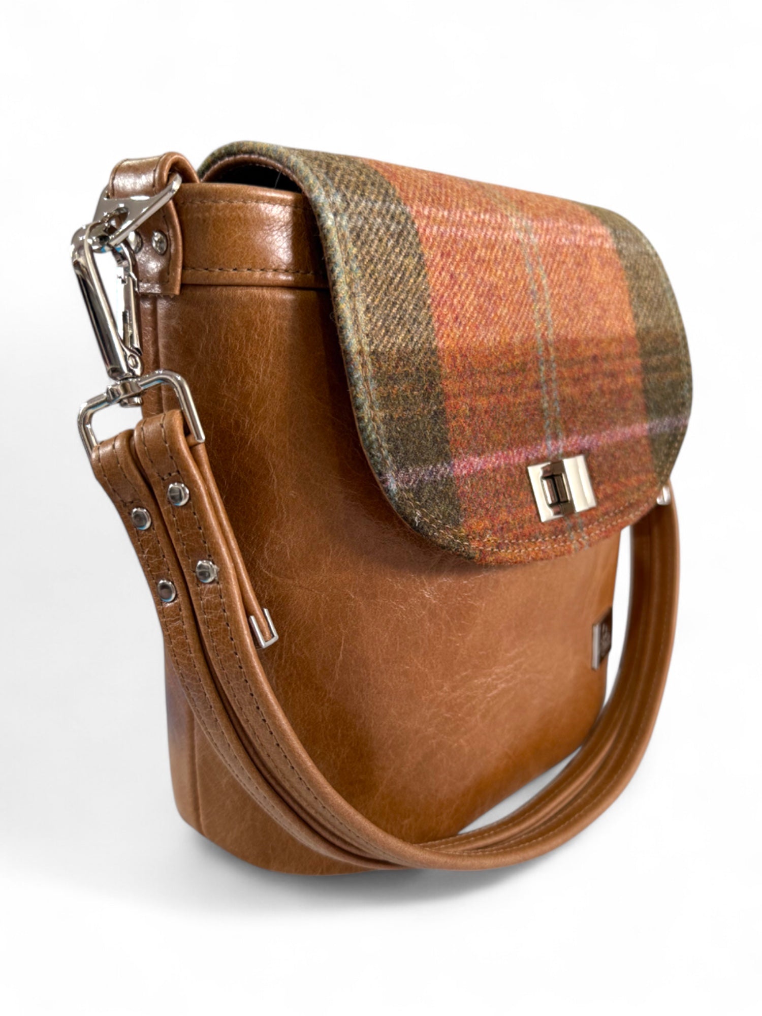 Close-up of leather strap and twist lock on Belle handbag, handcrafted in UK. The bag is on a white background
