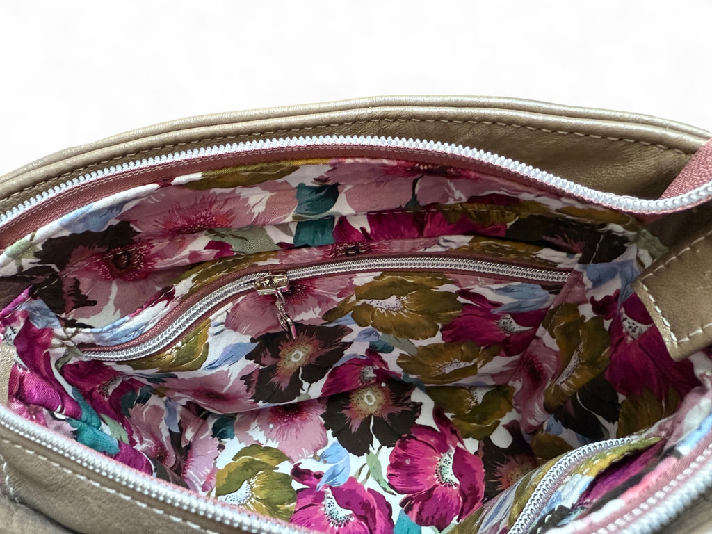 Inside view of the Belle bucket bag, showing the interior slip and zip pockets and floral lining.
