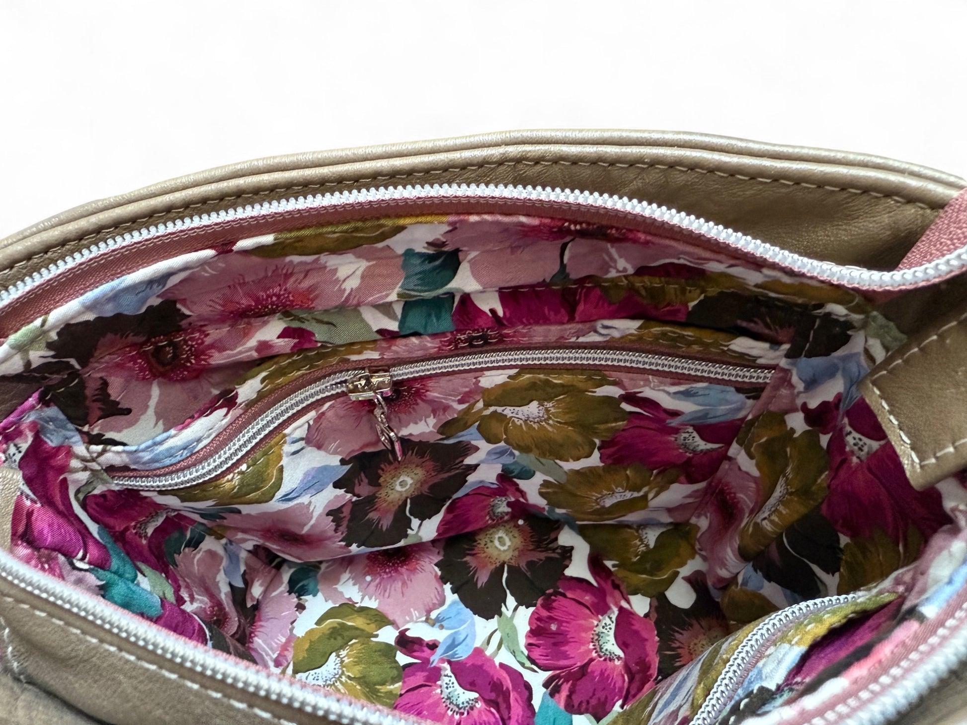 Inside view of the Belle bucket bag, showing the interior slip and zip pockets and floral lining.
