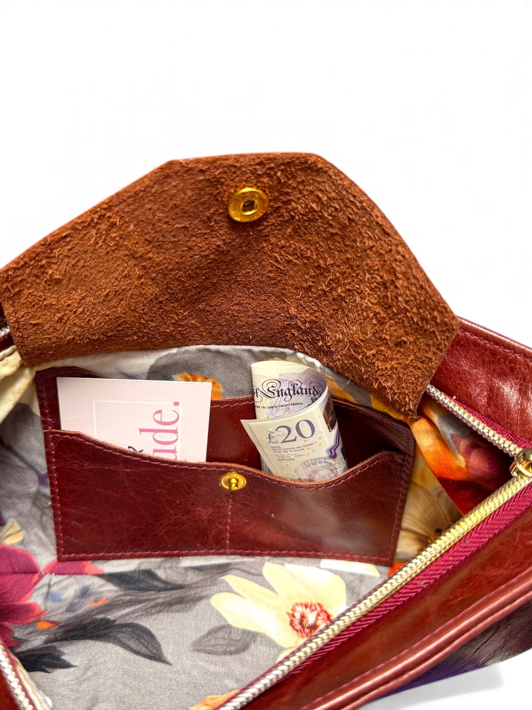 Interior shot of the Betty Bow clutch bag. It shows the flap of the integrated purse as open, with a bank or business card in one slot and a £20 note in the other. The image also shows that underside / suede side of the flap, proving that we use genuine leather