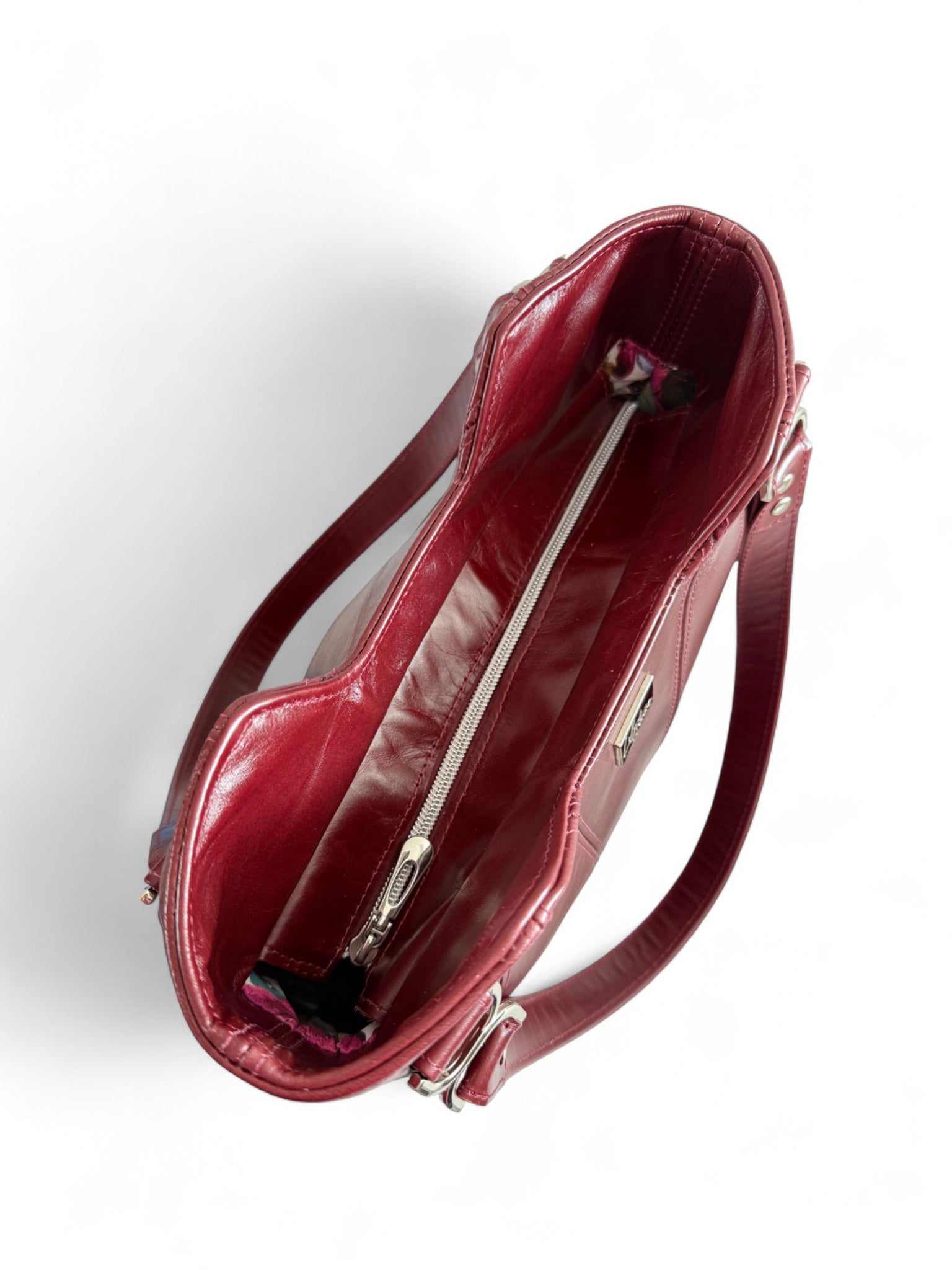 Birds Eye view of dark red, rescued leather Alaula handbag and silver hardware on a white background