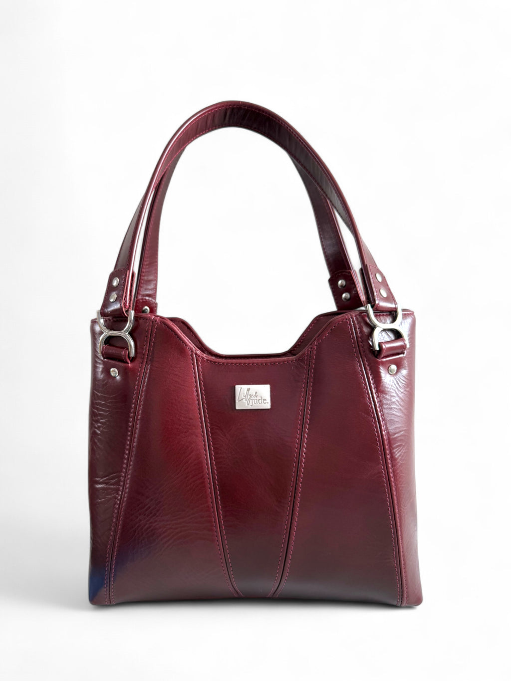Burgundy, maroon panelled leather handbag with silver hardware on a white background. The handles are up and it highlights the silver buckles on the front