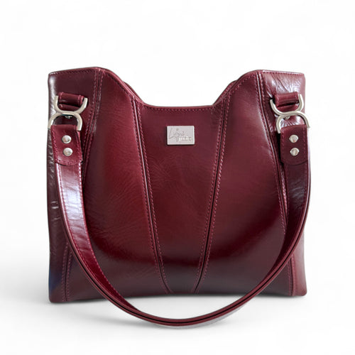 Maroon burgundy leather handbag with silver hardware on a white background. 