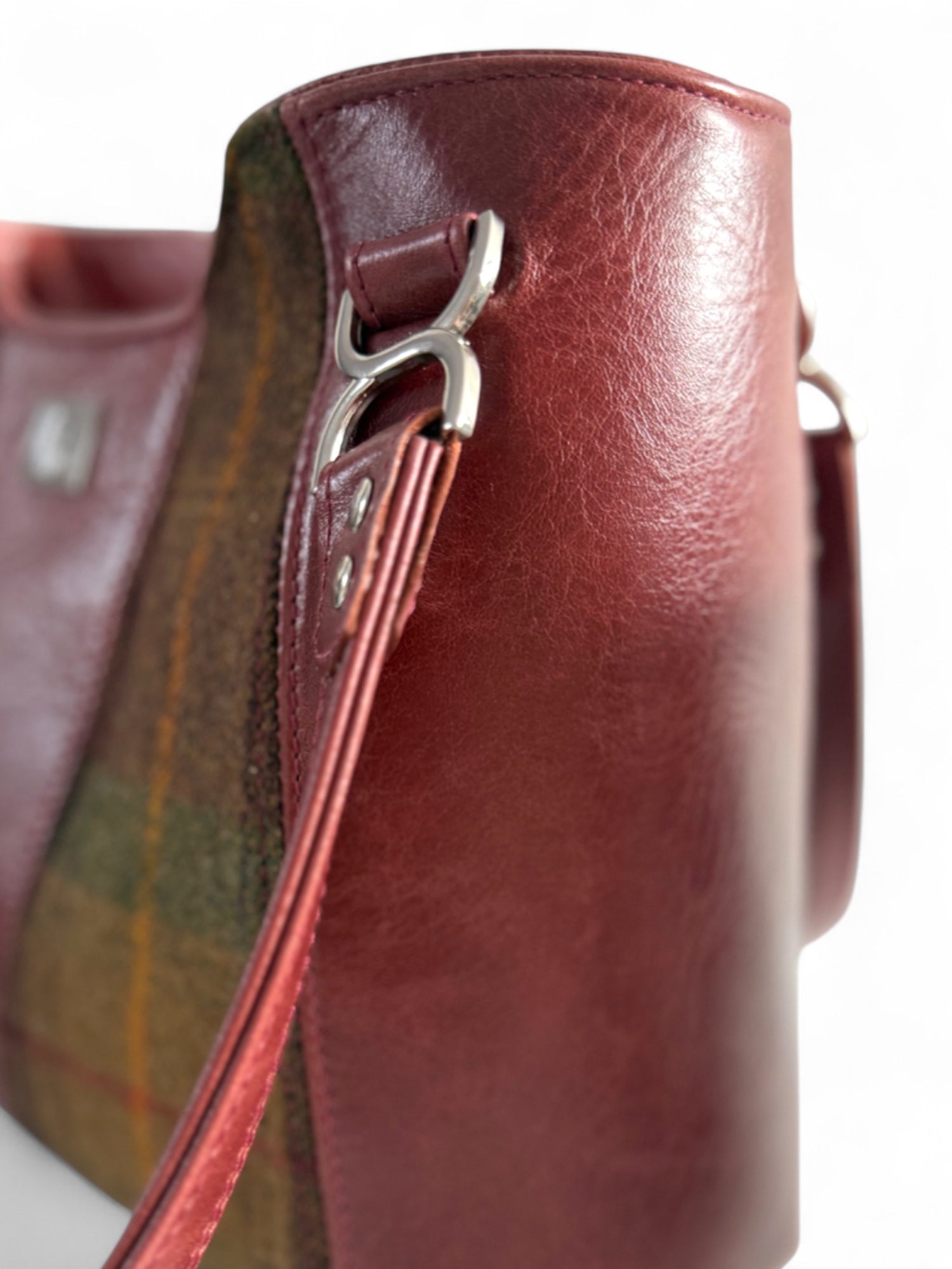 Close-up showing detailed leather and tweed textures and the silver strap connector.