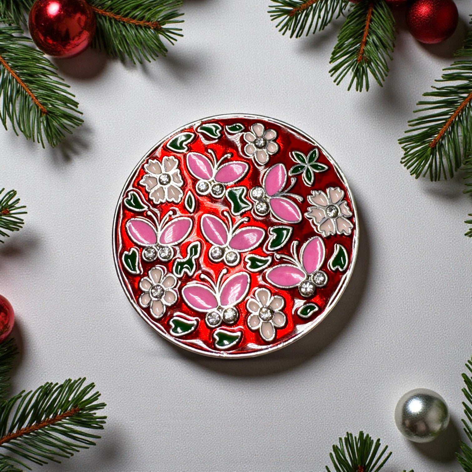 Decorative round plate with floral and butterfly design on a light gray background with Christmas decorations.