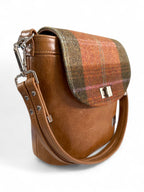 Close-up of leather strap and twist lock on Belle handbag, handcrafted in UK on a white background
