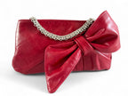 Red leather Betty Bow clutch bag with a large bow and silver bracelet chain detail on a white background. 