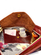 Interior shot of the Betty Bow clutch bag, showing the open flap of the integrated purse, with a bank card and a £20 note .