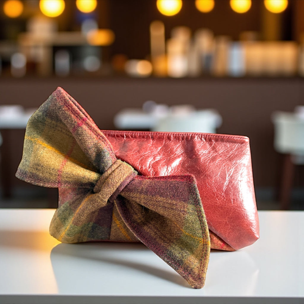 Red clutch with plaid bow on a white surface, blurred restaurant background
