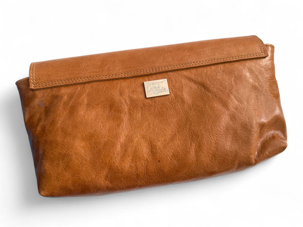 View of the back of the tan leather Bronte clutch bag, highlighting the Lilly & Jude logo tag.