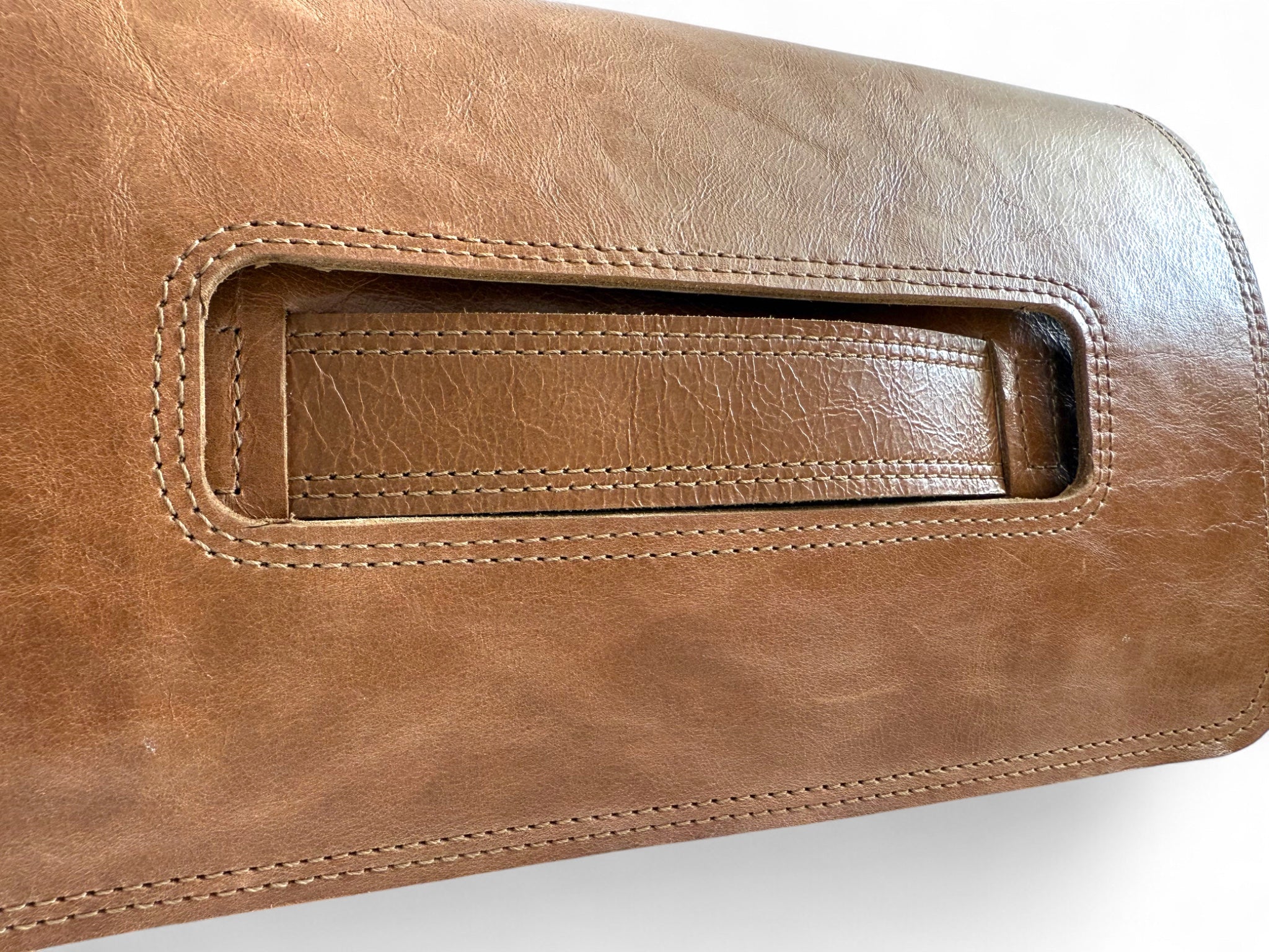 Close-up of a tan  brown leather bag with a handle on a white background