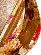 Interior view of the Bronte clutch bag by Lilly & Jude. It shows the floral lining fabric, leather trimmed zipper pocket and the signature integrated leather purse