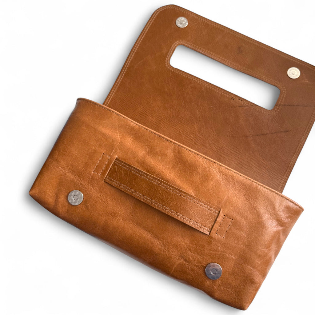 Tan Bronte clutch bag, lying down on a white background with the flap lying open. The image shows the scarring and texture on the leather, which was rescued from heading to landfill 