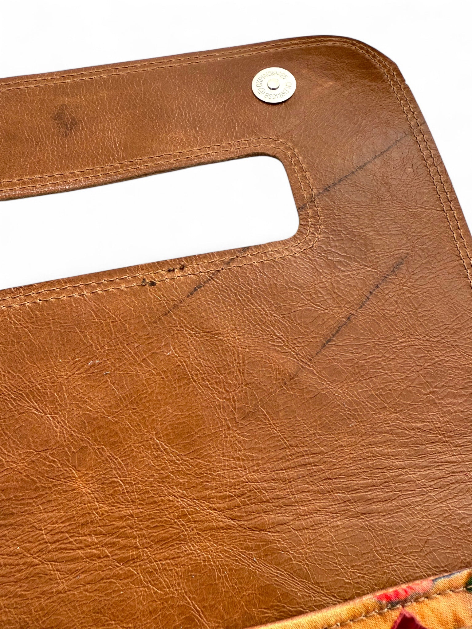 Close up view of the underside of the flap on the tan coloured Bronte clutch bag, highlighting the scars and imperfections in the rescued leather