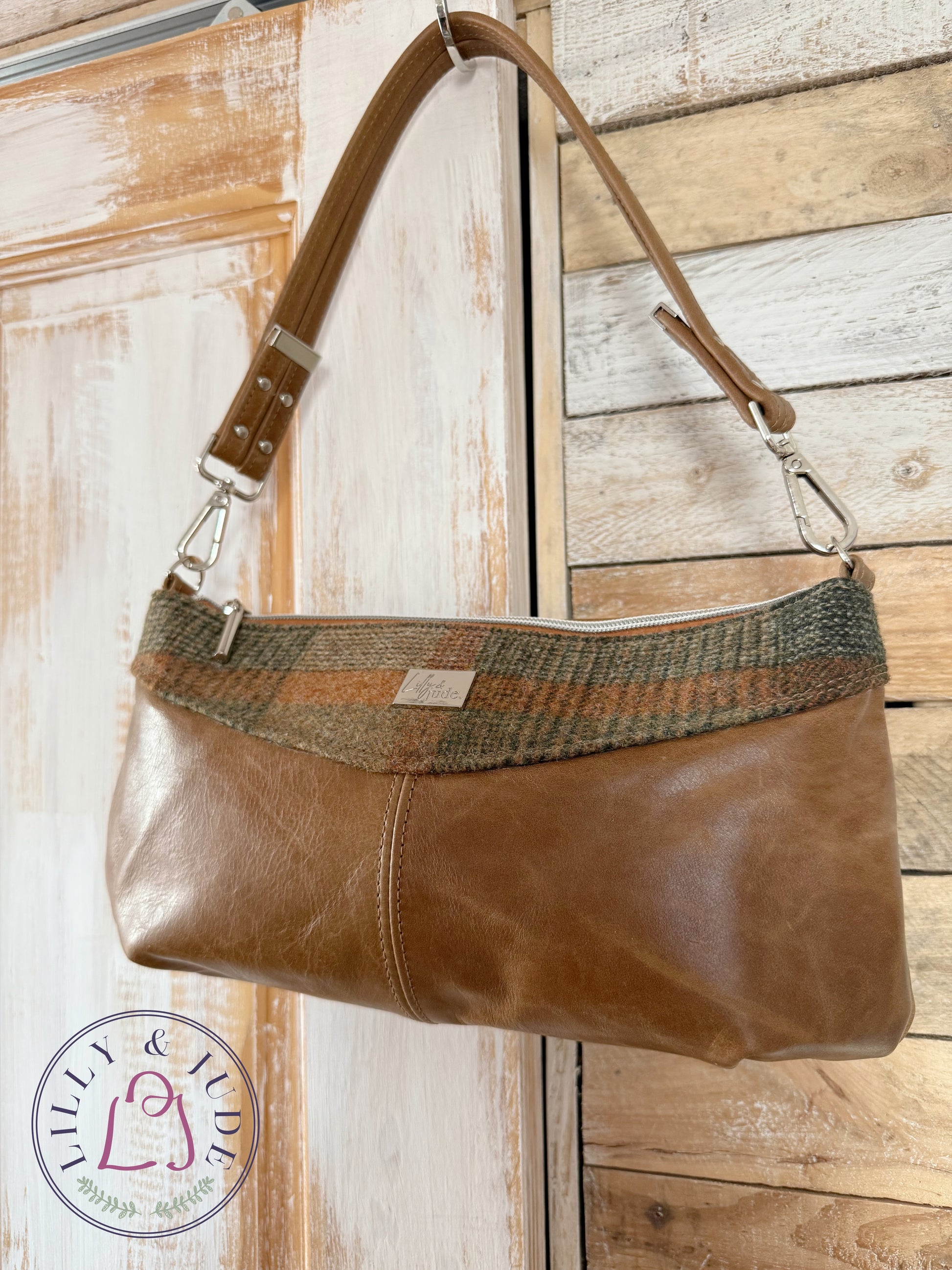 Elland handbag in tan leather and tweed hanging on rustic door with silver hardware.
