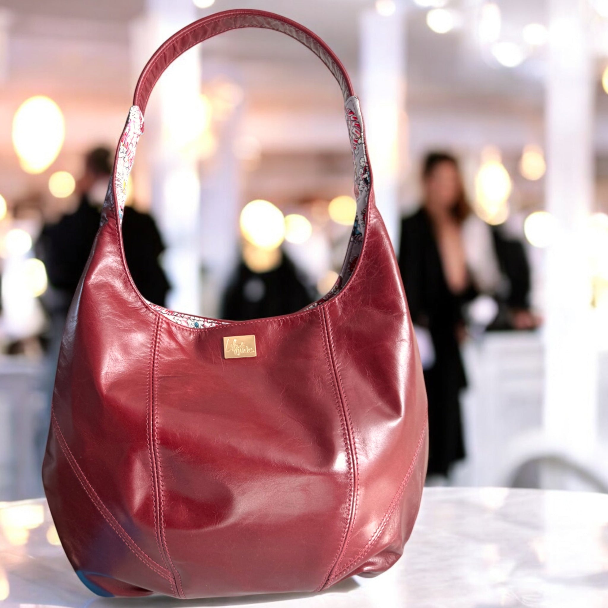 Red leather slouchy handbag on a table with blurred background
