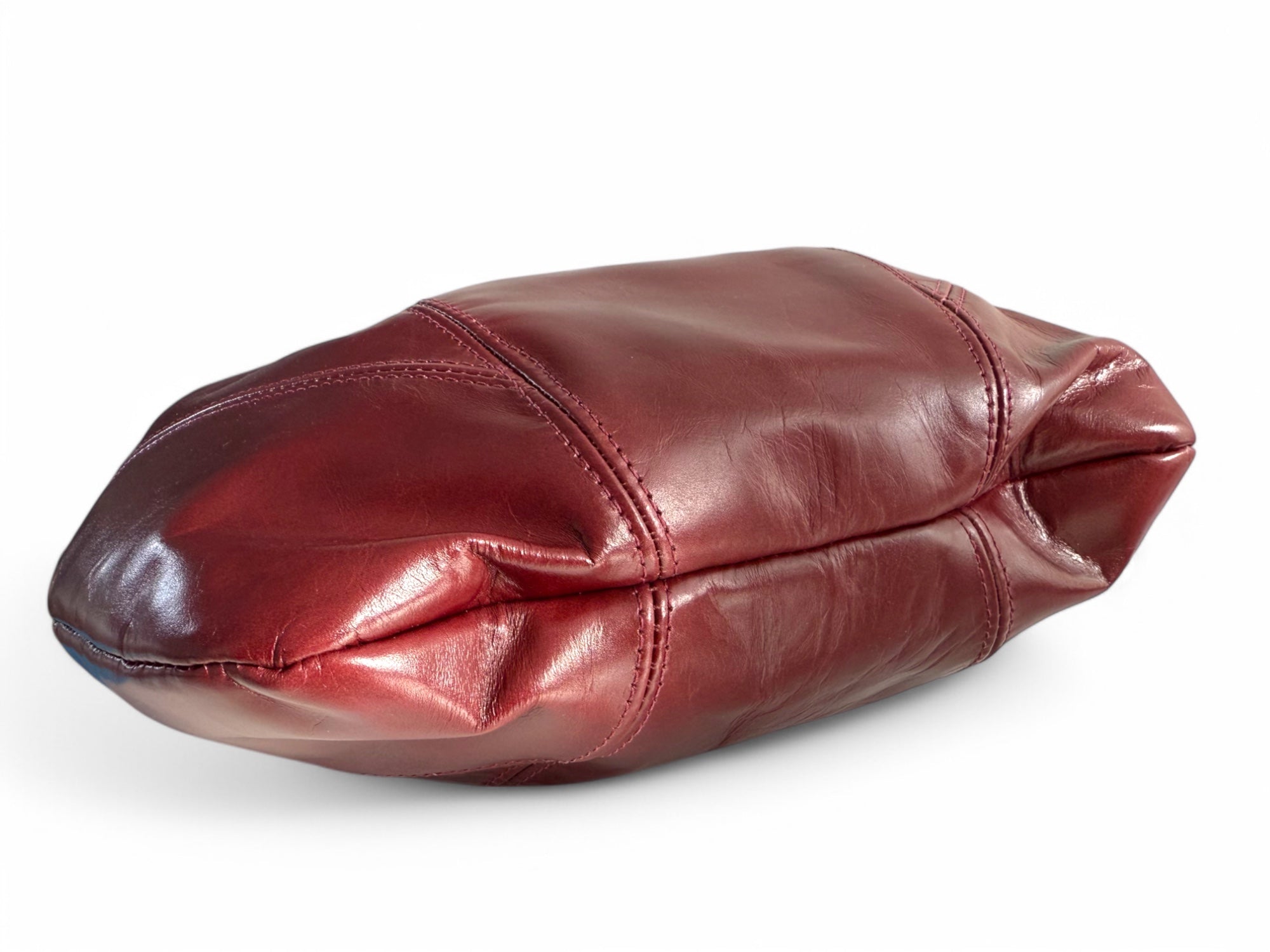 View of the bottom of a deep red leather slouchy handbag on a white background