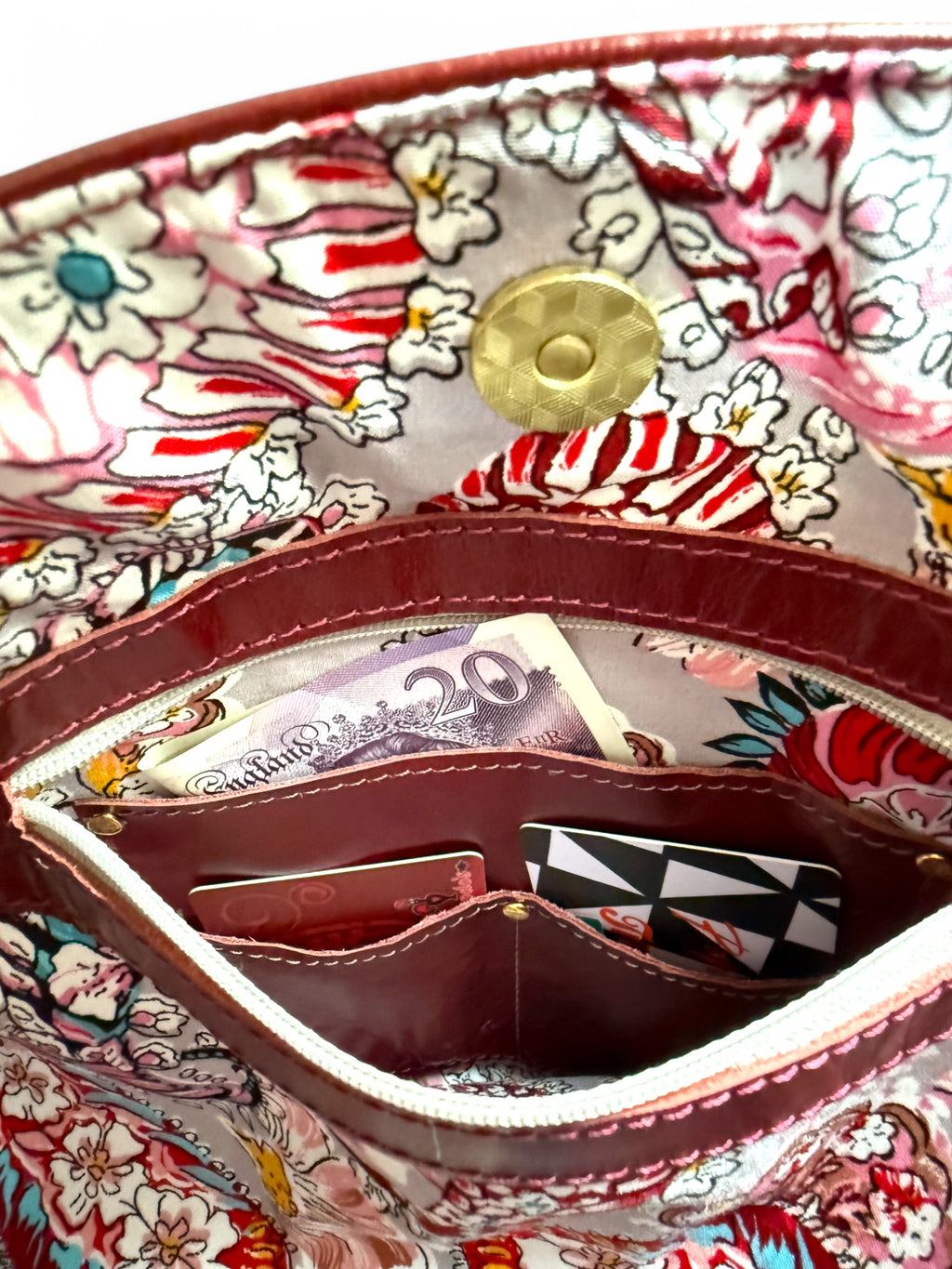 View of the paisley patterned lining and integrated leather wallet with money and card visible.