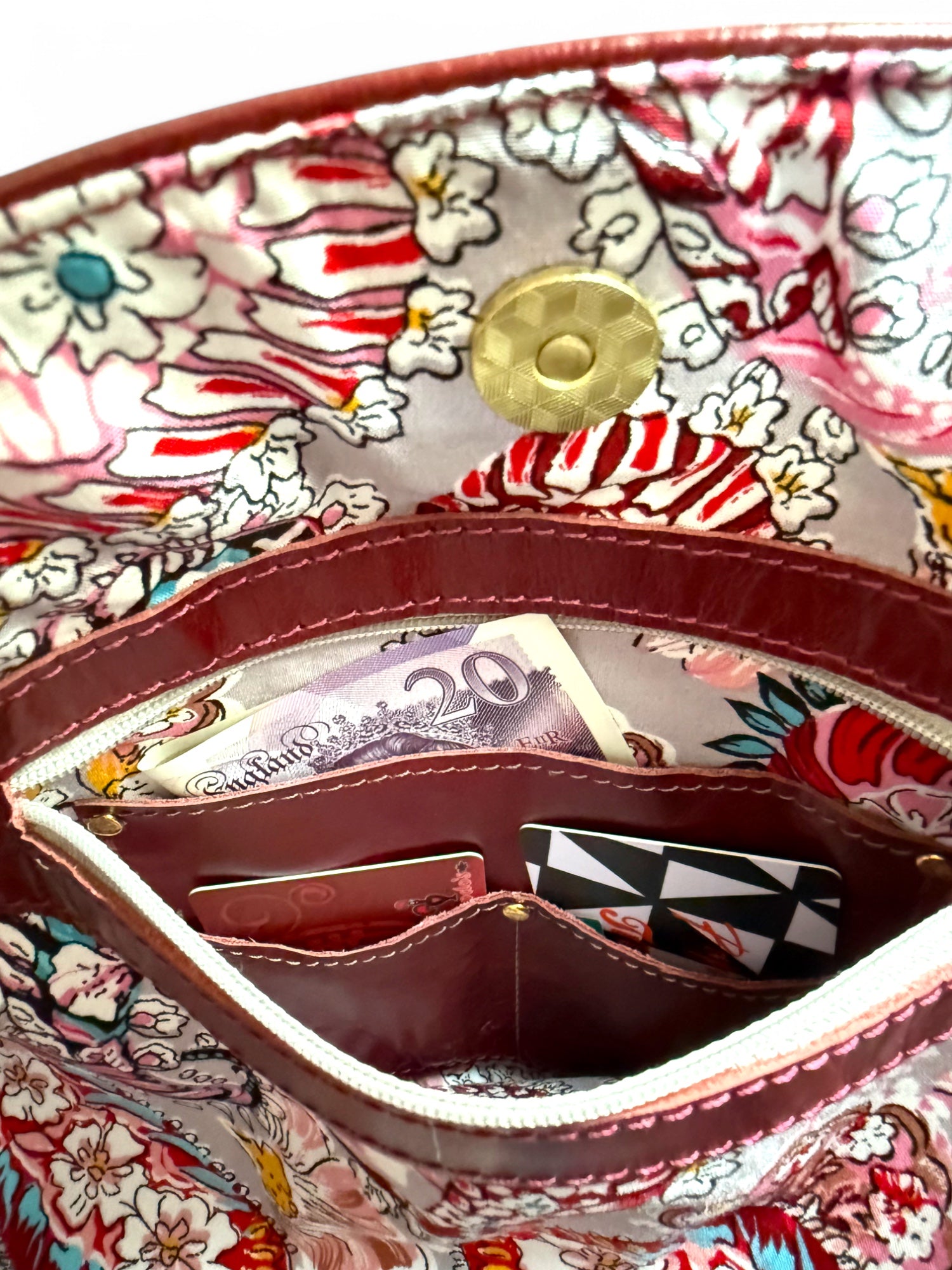 View of the paisley patterned lining and integrated leather wallet with money and card visible.