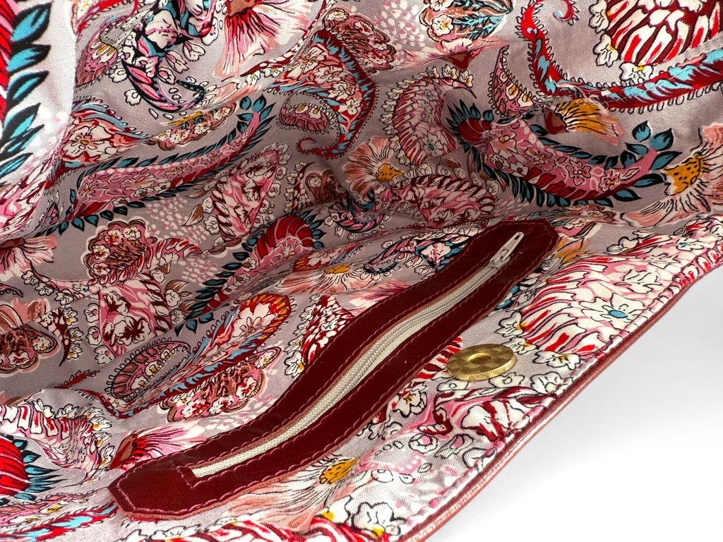 Close-up of a colorful paisley patterned lining of a burgundy leather slouch handbag, highlighting the interior zipper pocket
